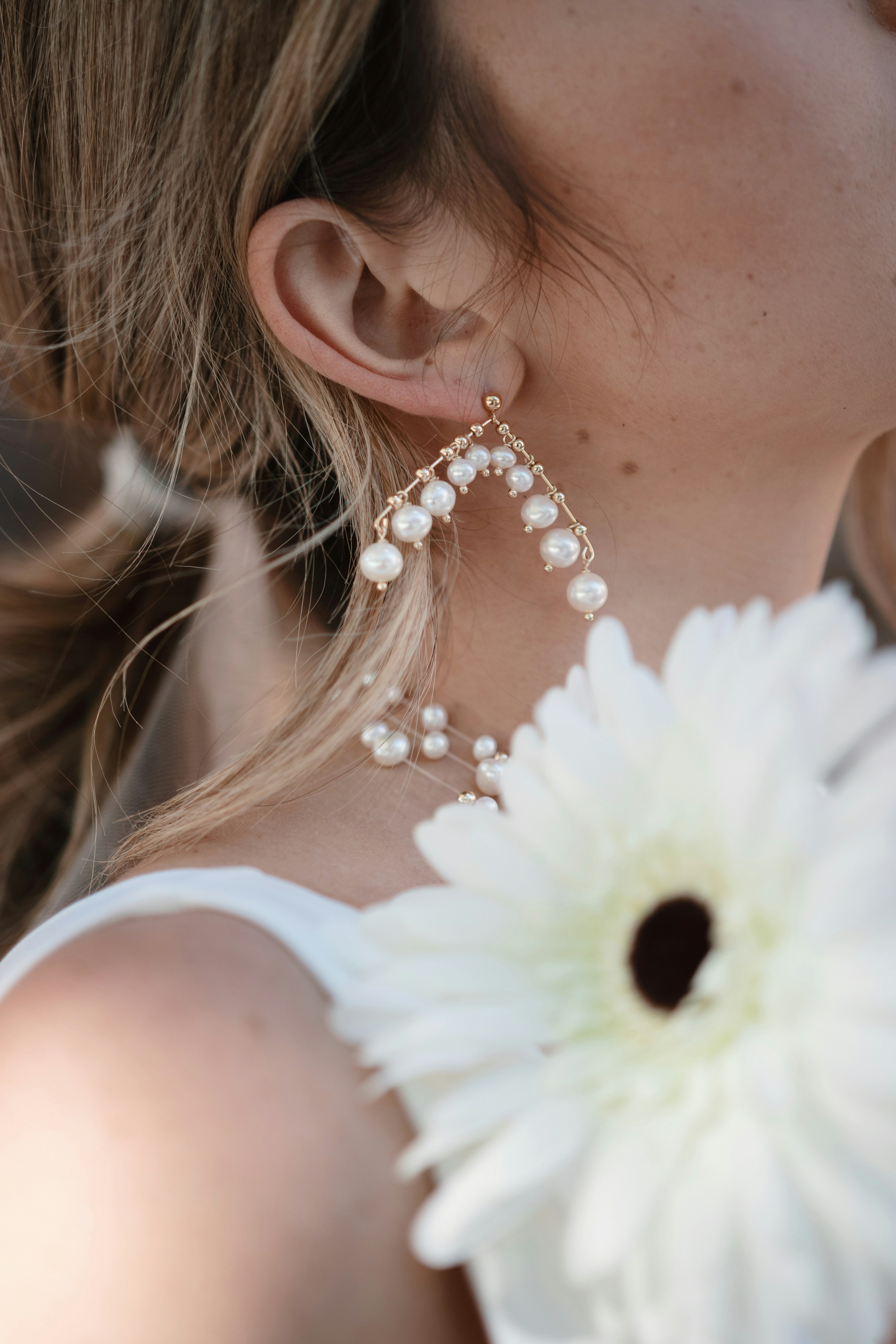 woman in white floral tank top with white flower on ear